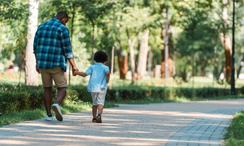 father holding sons hand walking